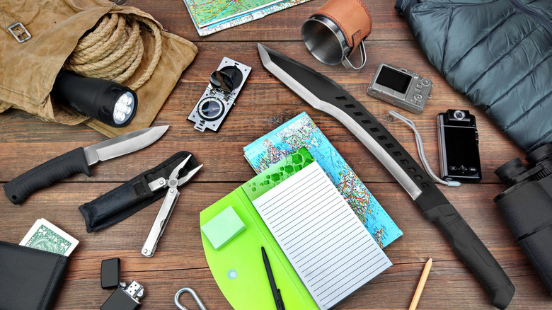 Camping gear items on a table, along with pen and paper.