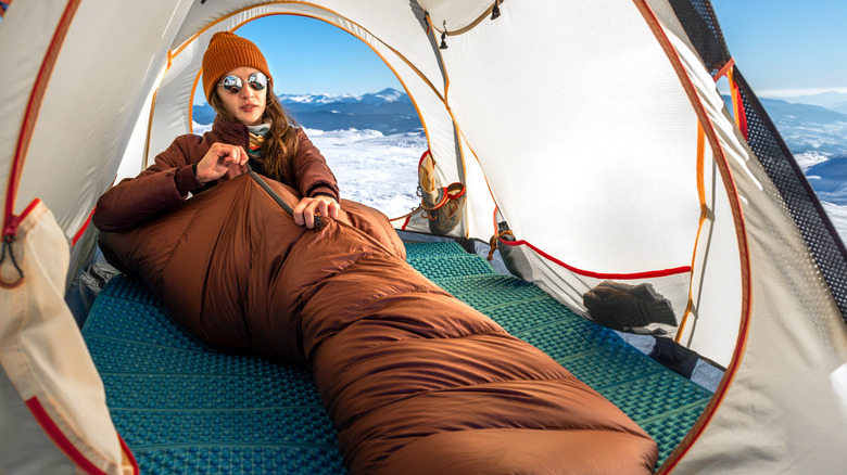 Woman zipping up sleeping bag in winter climate