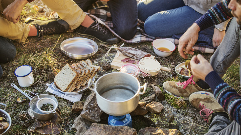 Foods being prepared at a campsite by a group of friends.