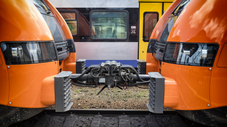 An image of two orange train locomotives attached on the tracks