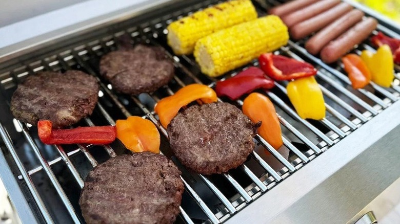 Grill with burgers, vegetables, and hot dogs