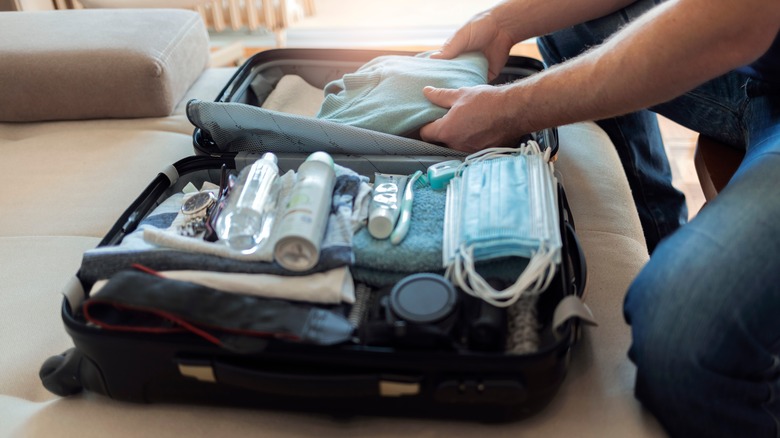 man packing suitcase with essentials