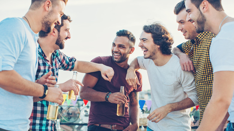 Male friends bond over beers outside.