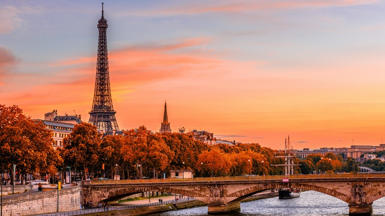 Eiffel Tower and bridge over river with orange and blue sky