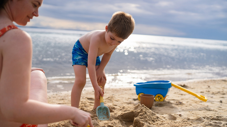 a woman and boy playing in the sand at the beach