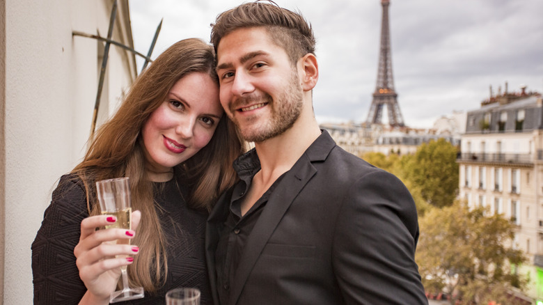 A couple drinking champagne on a Parisian balcony.