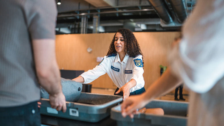 TSA officer moving bin down conveyor belt