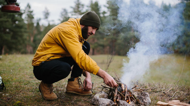 man building up a campfire