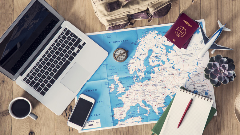 map of Europe, laptop, notepad, phone, passport