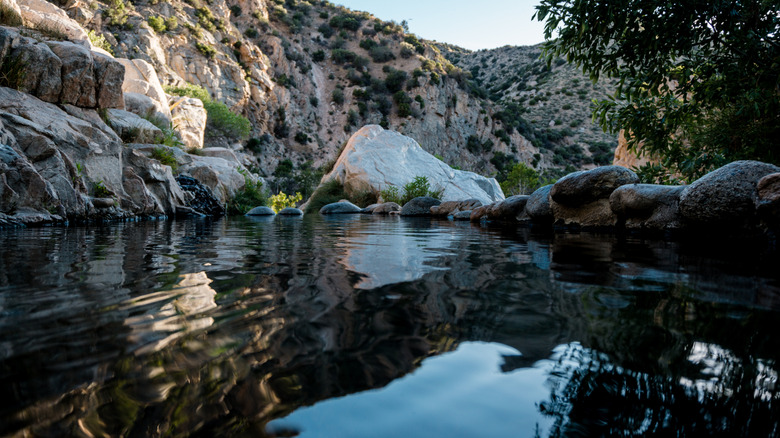water-level view of a hot spring surrounded by canyon cliffs