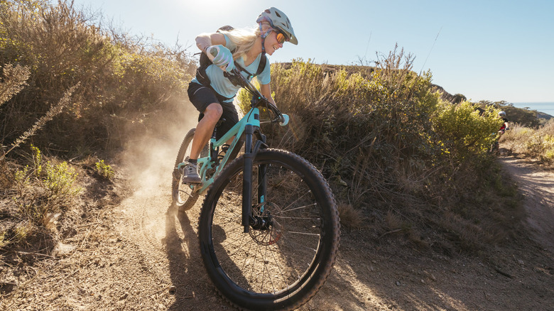 A mountain biker smiles as she bombs down a dusty trail