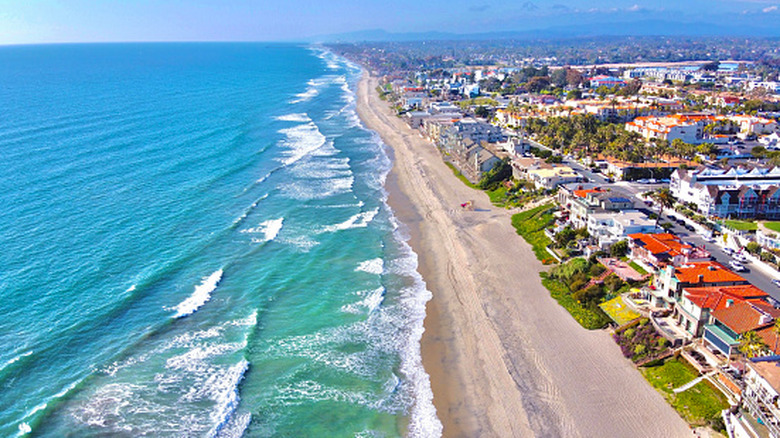 Aerial shot of the beach and coast of California with homes along the sand.