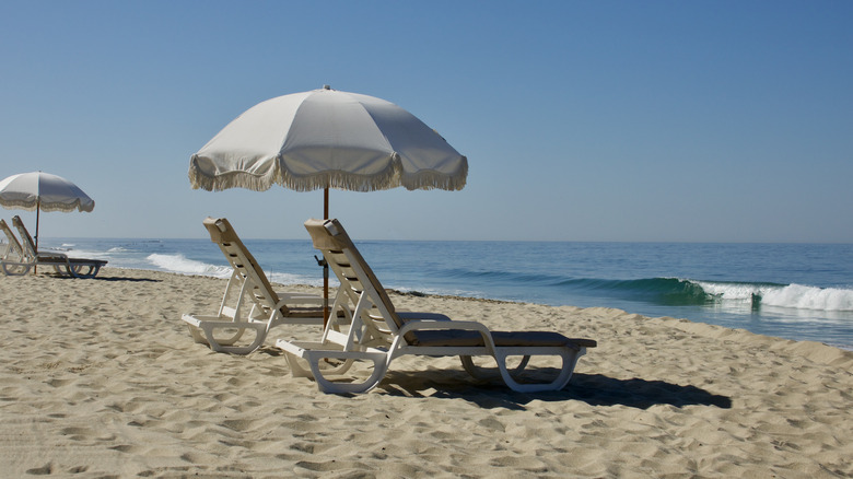 Beach lounge chairs and a sun umbrella on the water's edge in Laguna beach
