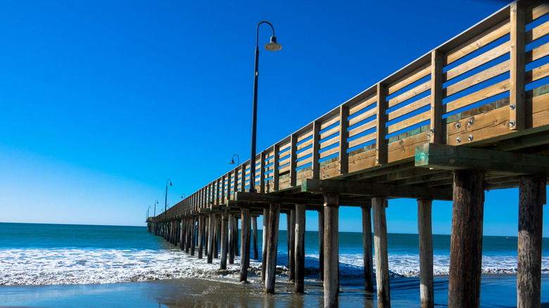 The historic wooden Cayucos Pier jutting into Estero Bay at Cayucos State Beach in Cayucos, San Luis Obispo County, California