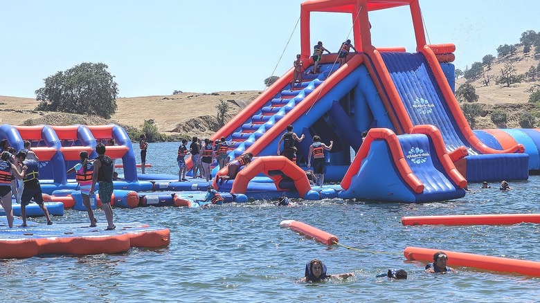 close-up view of guests playing on red and blue inflatable slides and obstacle course at Splash-n-Dash Aqua Park
