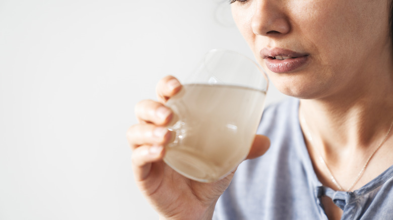 A woman holding a glass of dirty water