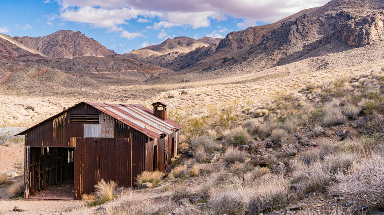 Rusted shack on the bottom left corner and a big open mountainous valley behind it