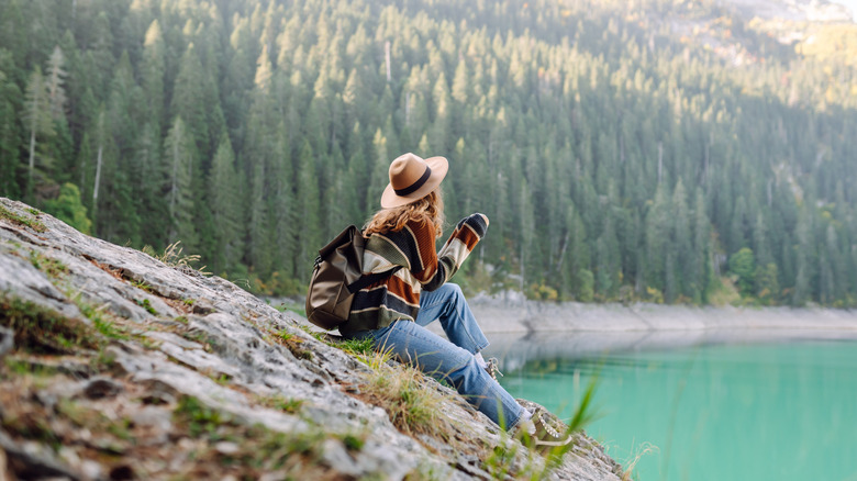 Back view of a woman traveler with hiking backpack on a high-mountain lake.