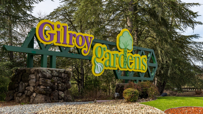 A Gilroy Gardens sign outside the theme park, with green grass and trees in the background
