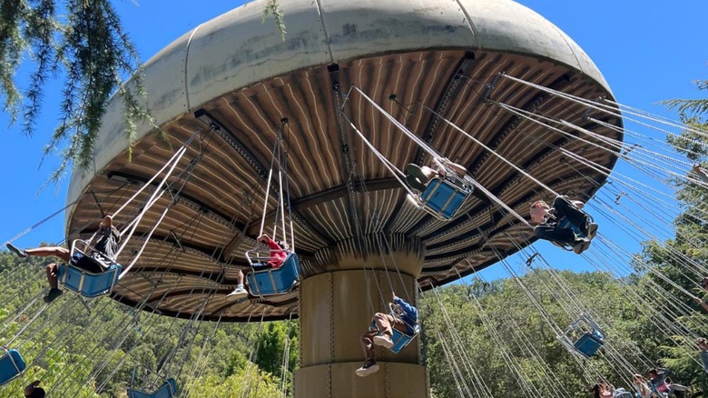 Kids riding on a flying swing shaped like a mushroom