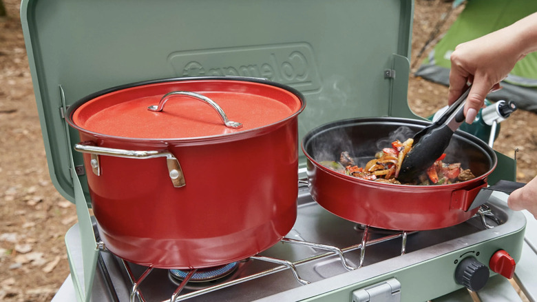 the Coleman Classic 2 burner stove in use with two pans on top cooking