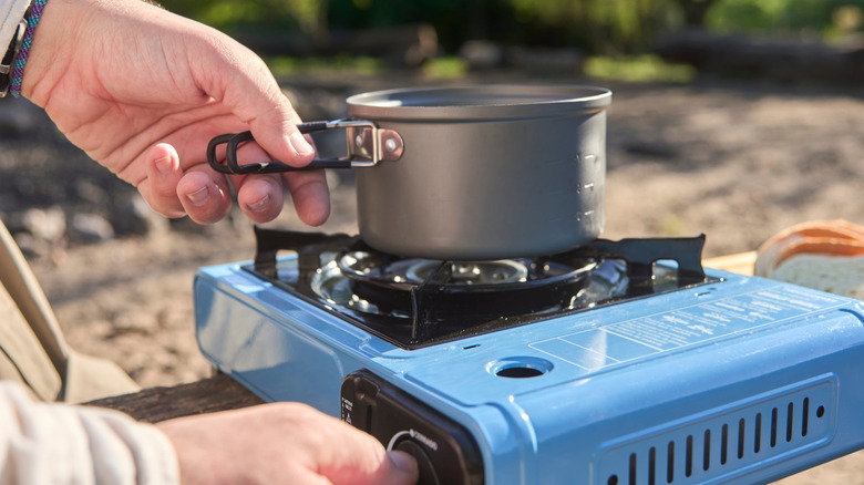 someone heating water on a single burner camp stove