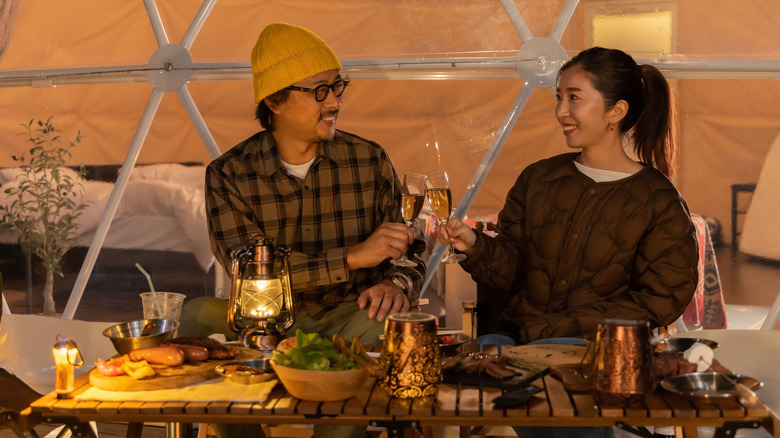 Two campers enjoying a meal outside a glamping tent