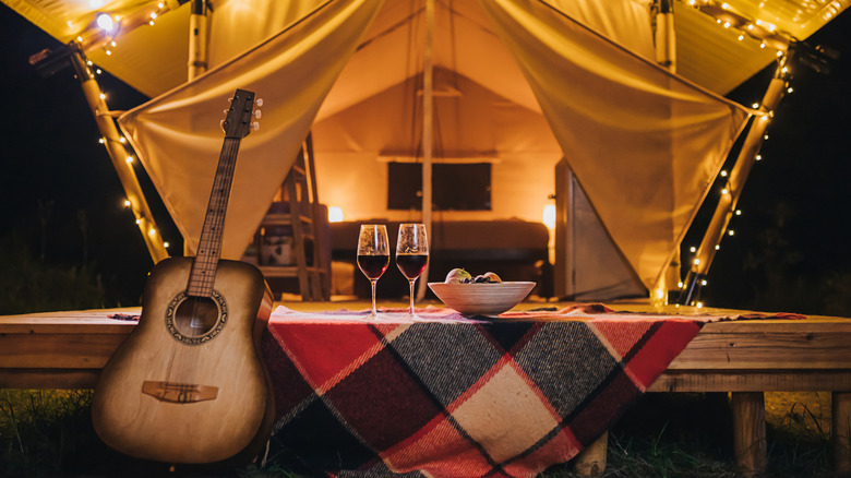 A glamping set up on a deck with a bell tent and string lights