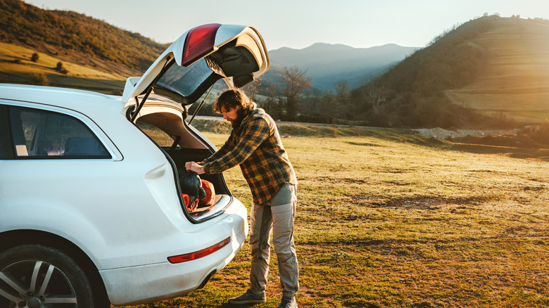 A man packing a car during a road trip.