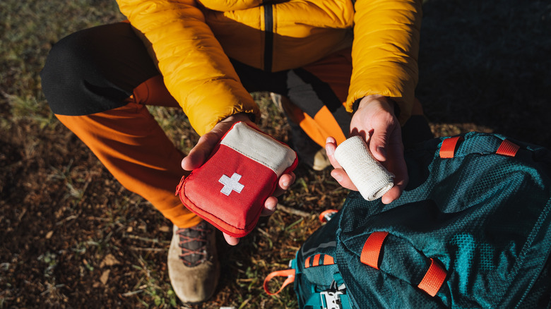 A camper holding a first aid kit and gauze.
