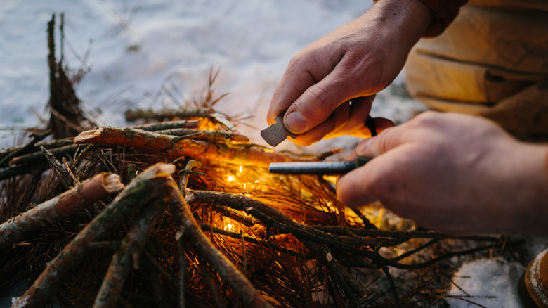 a man's hands showing how to light a fire