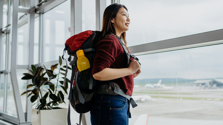 person with backpack at airport with reusable water bottle