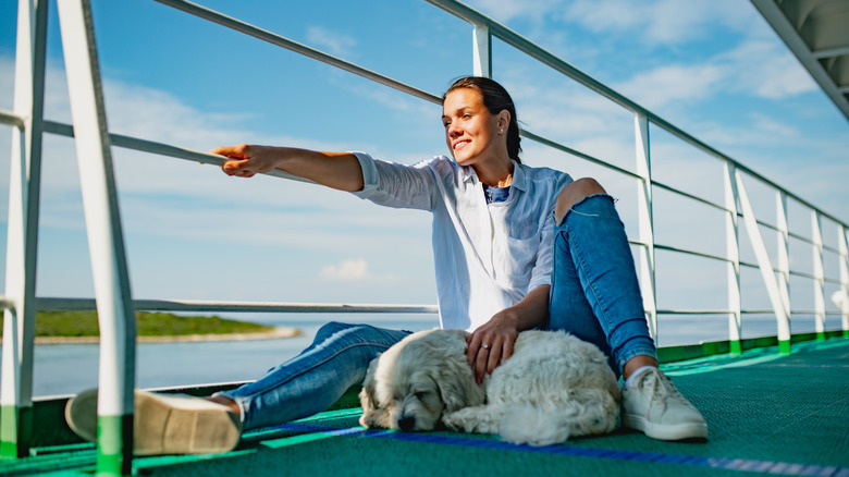 Traveler relaxing with dog on boat deck
