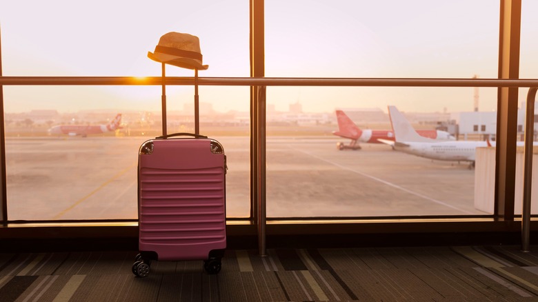 Pink suitcase with hat at airport