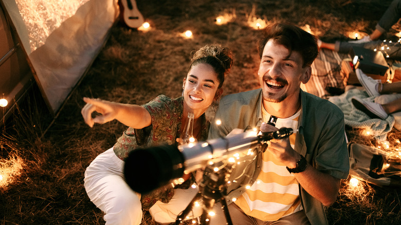 Couple stargazing together with a astronomical telescope while being on a romantic date