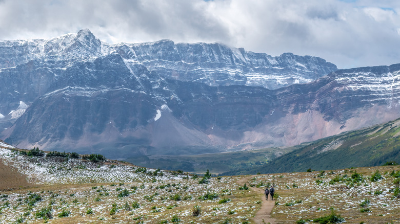 Large mountain and walking trail with two people hiking