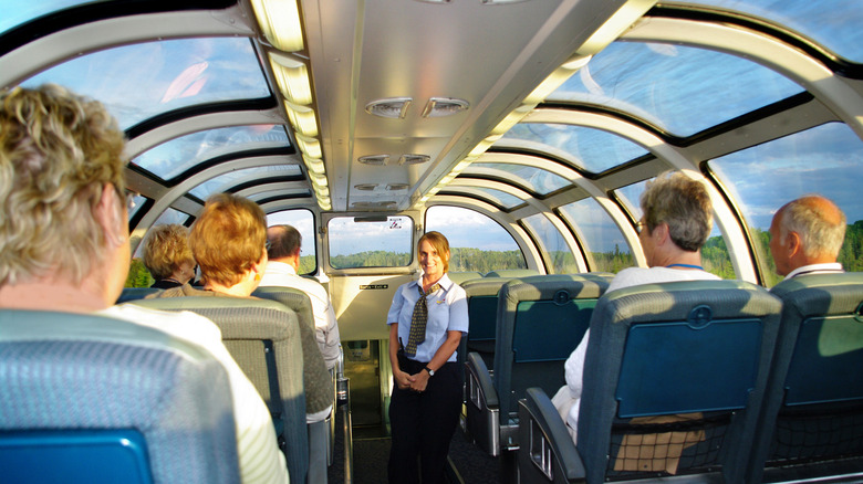 A train employee with passengers in a glass-domed car