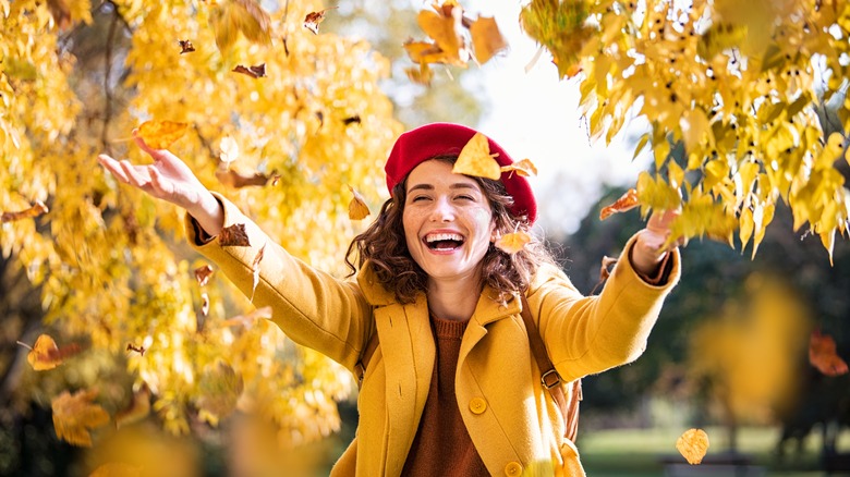 Woman throwing autumn leaves