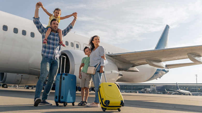 a family of four with suitcases wait to board a plane