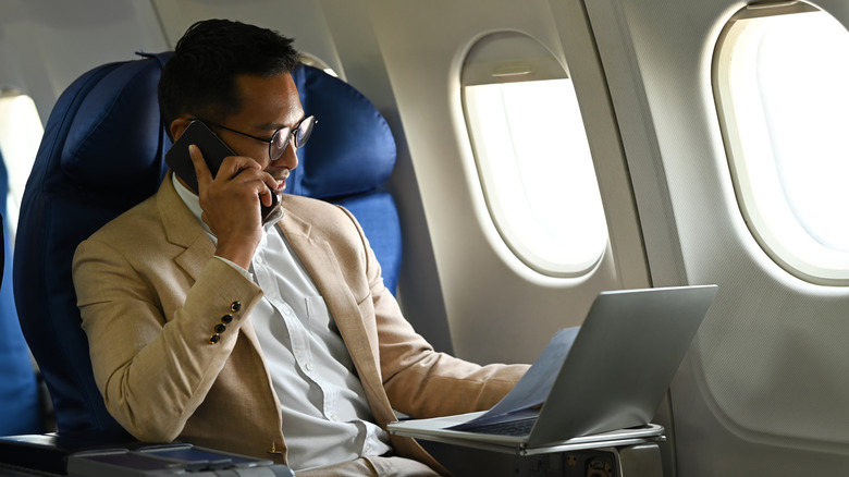 a man on an airplane using his laptop and in-flight Wi-Fi
