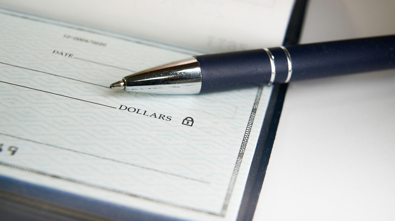 A close-up of a ballpoint pen and a check.