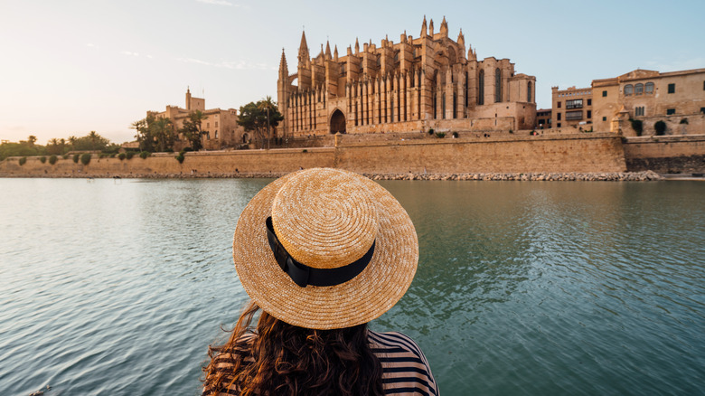 woman wearing a straw hat admiring the Cathedral de Santa María de Palma de Mallorca