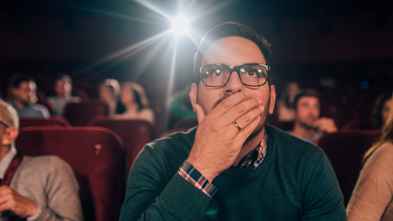 Man covering mouth movie theater