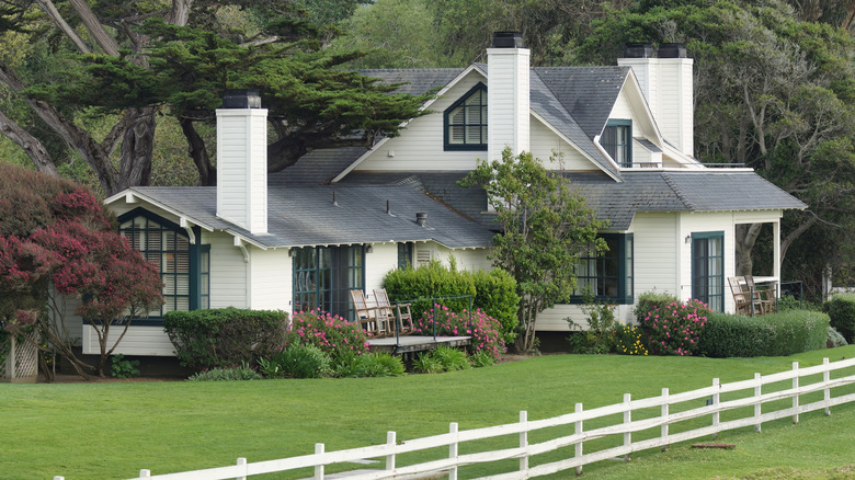 Mission Ranch with chimneys, rocking chairs on the patio, and a white fence.