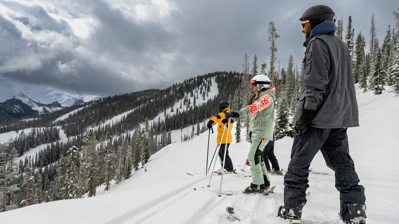 A group of people standing at the top of a ski run getting ready to go
