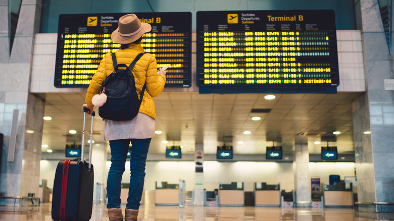 Woman reading airport departure sign