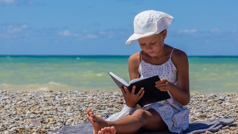 child reading on the beach