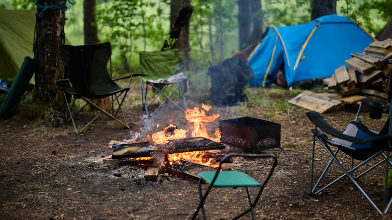 campsite with campfire, chairs, and tents