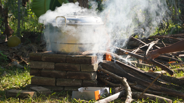 steaming metal pot over outdoor fire stove