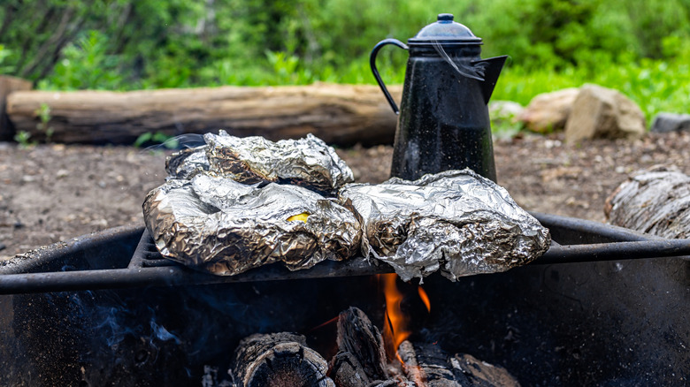 A close-up of foil pockets on an open grill.